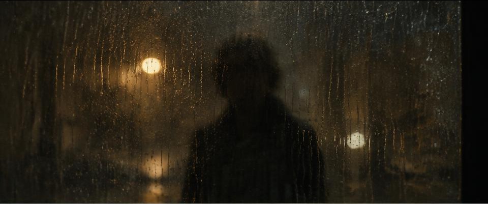 A silhouette seen through rain-covered glass