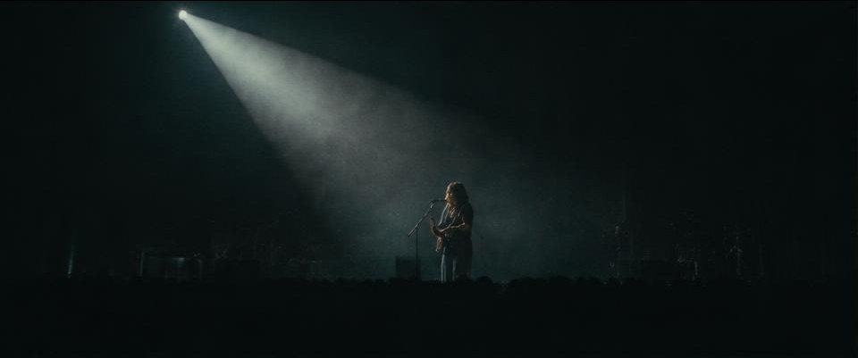 A performer beneath a single beam of stage light